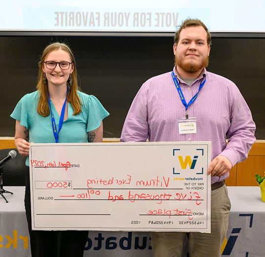 two people, man and women, holding giant check